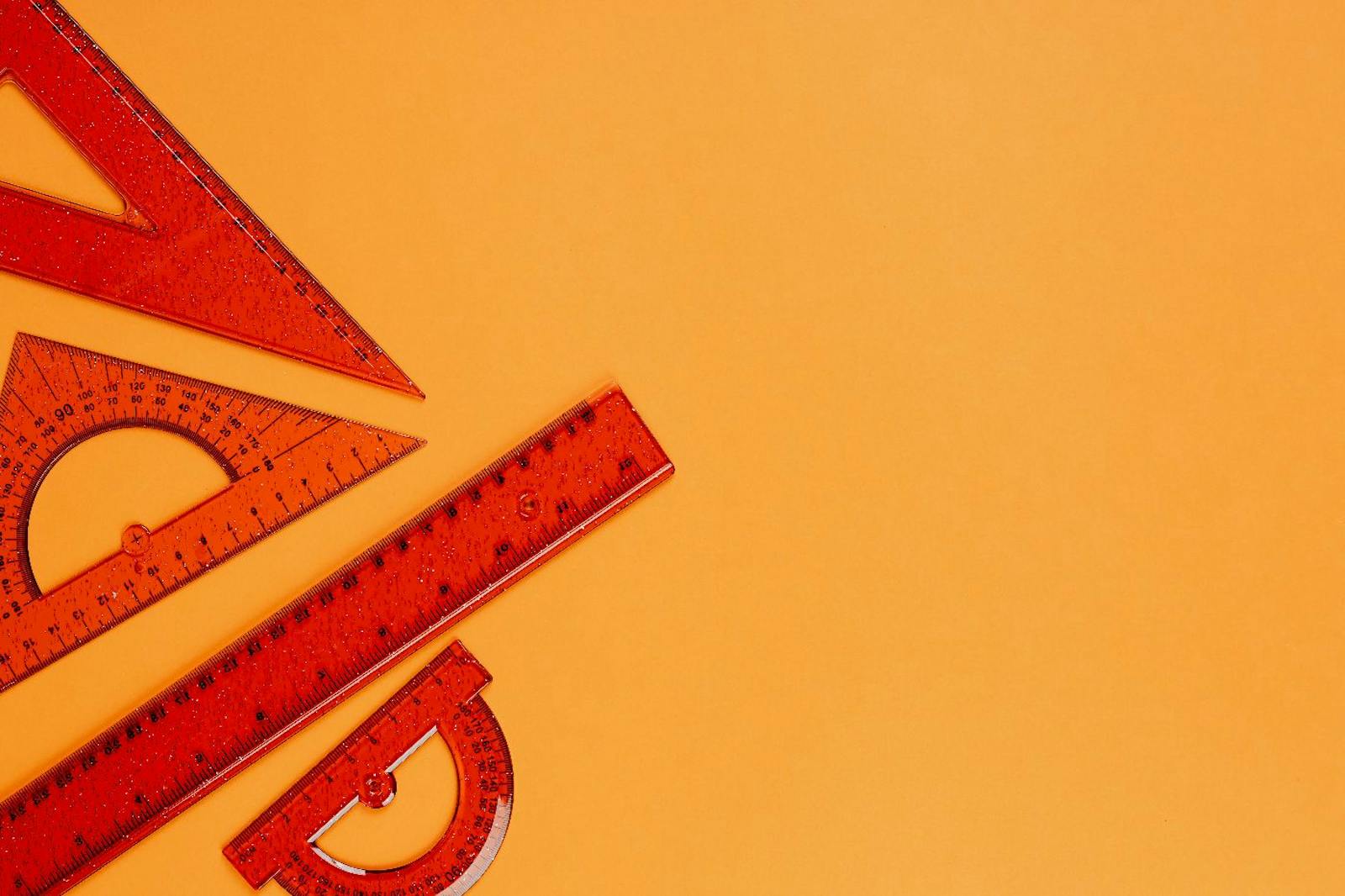 Orange rulers and protractors illustrating measurement and analytics